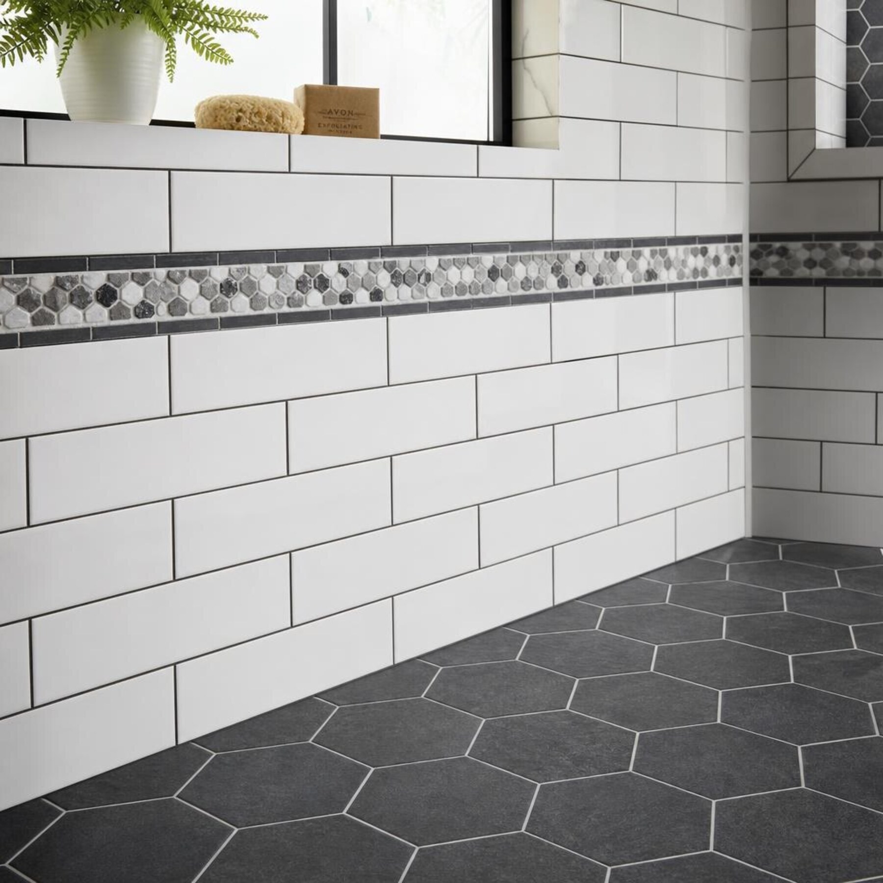 Bathroom with charcoal hexagon mosaic floor tile and elongated white subway wall tile with precise dark grout lines